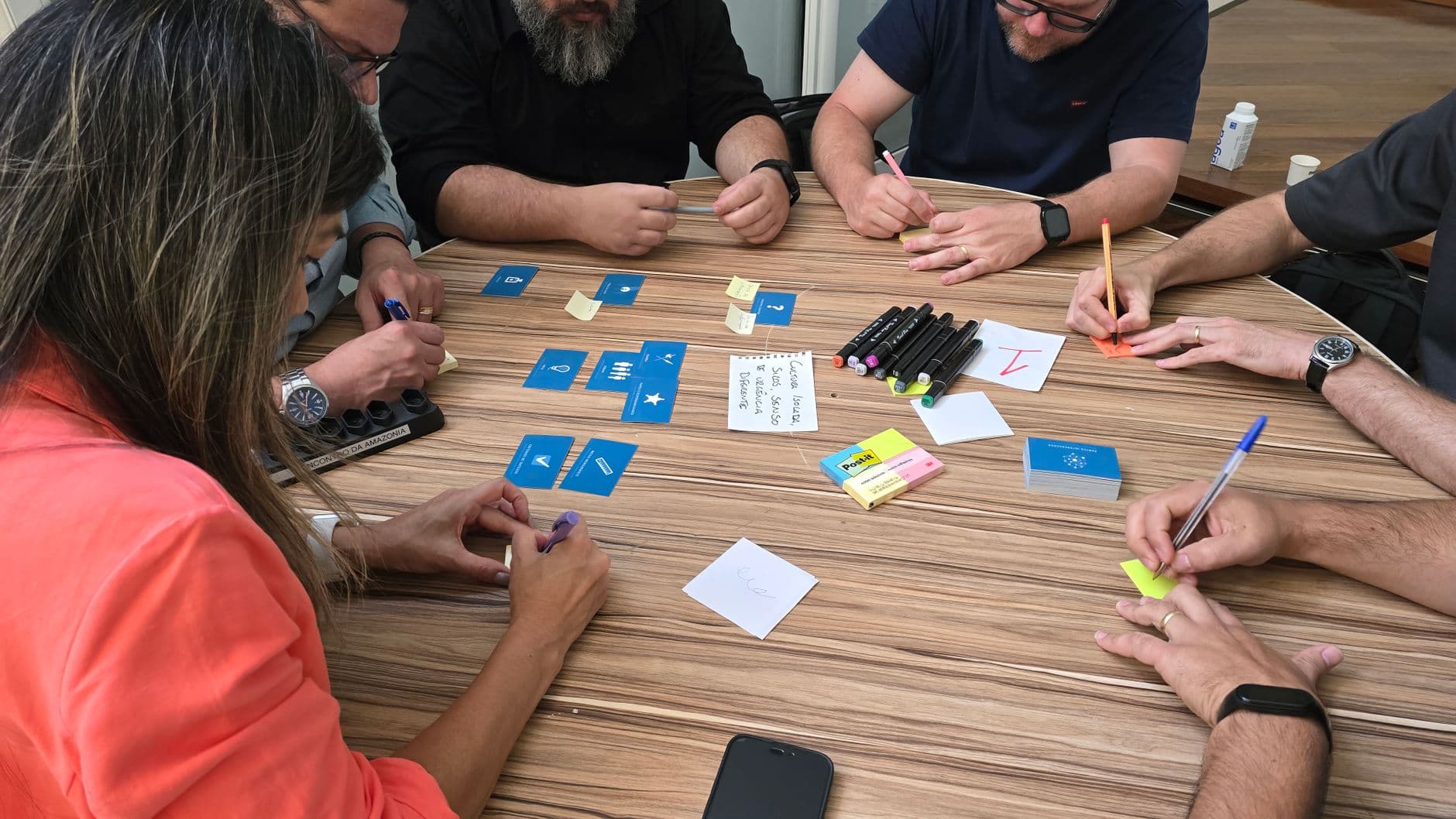 Diverse team engaged in a brainstorming session with cards and sticky notes on a round table.