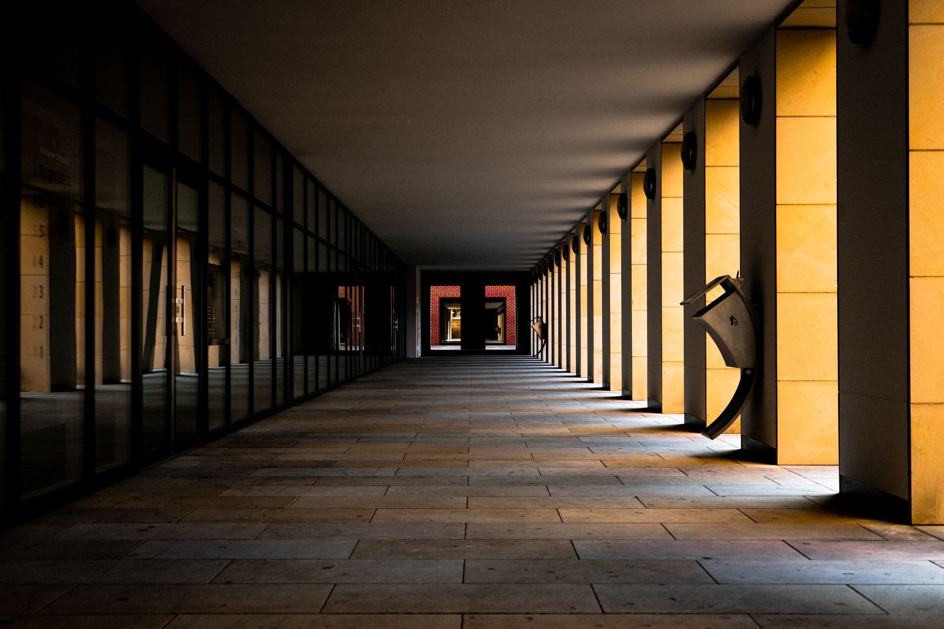 Dramatic view of an empty symmetrical corridor with striking golden columns casting shadows.