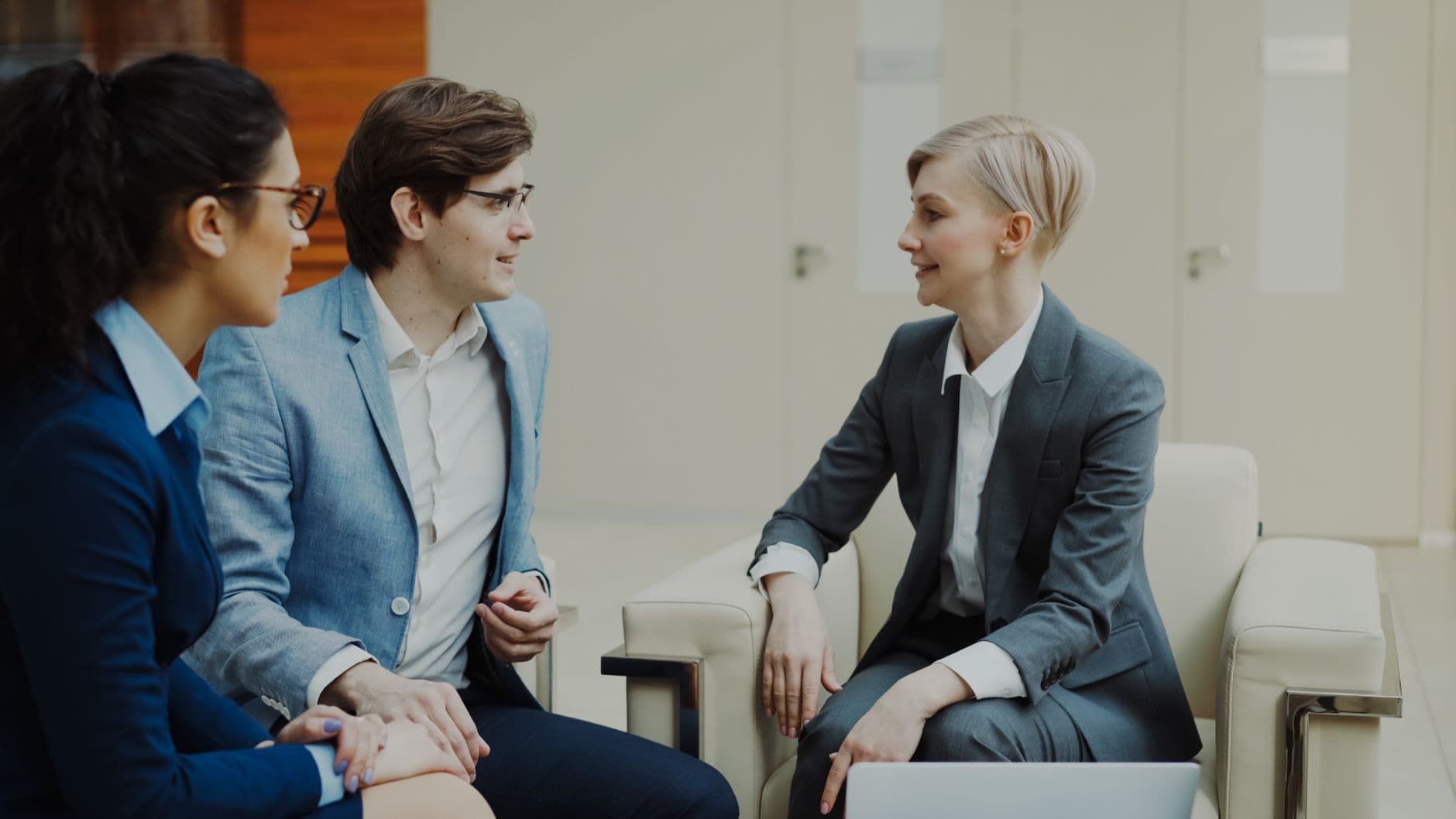 Three professionals engaging in a conversation during a business meeting indoors.
