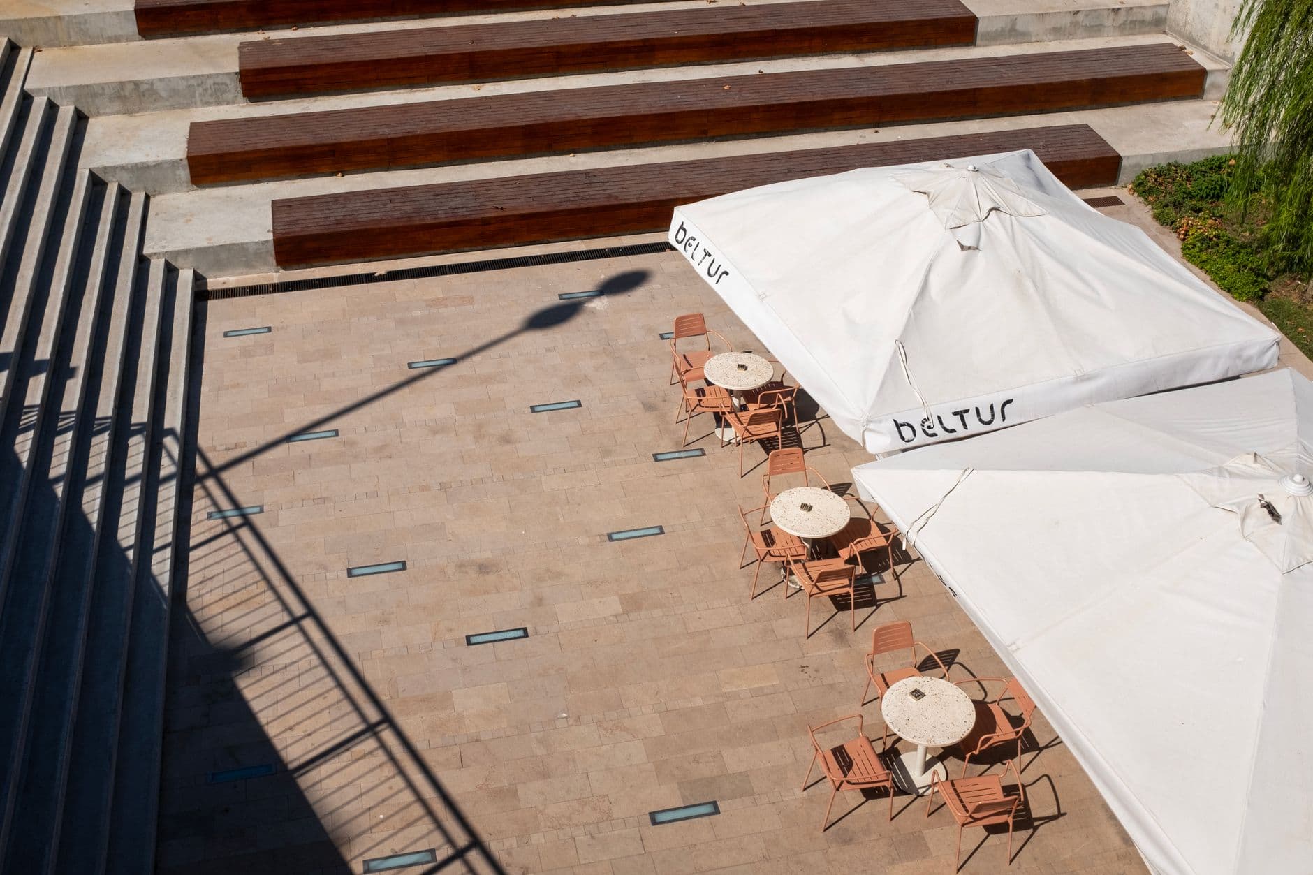 Aerial view of an outdoor café in İstanbul with modern seating and large sunlit umbrellas.