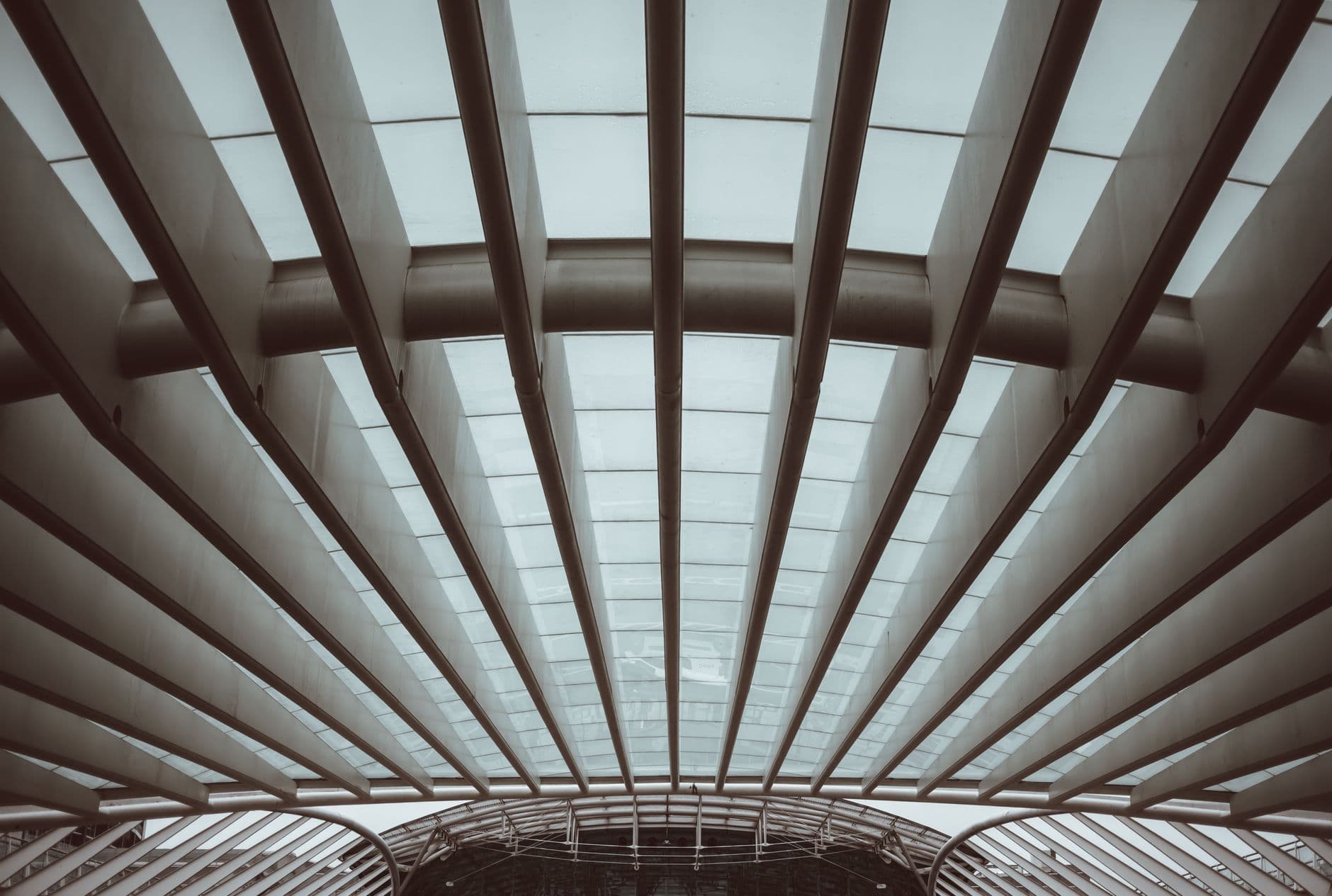 From below of glass geometric ceiling with metal beams in contemporary building in daylight